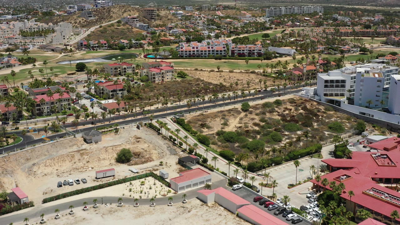 Aerial view of residential buildings, roads, construction lots, and dry hills.