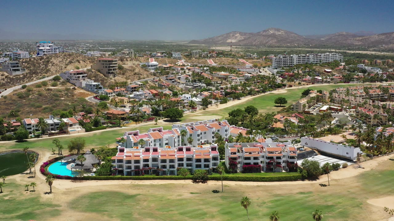 Aerial view of resort buildings beside a golf course and pool