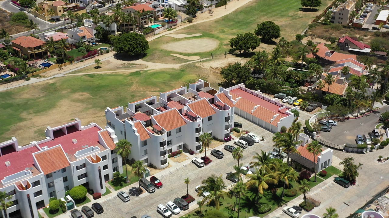 Overhead view of white apartment buildings beside a golf course.
