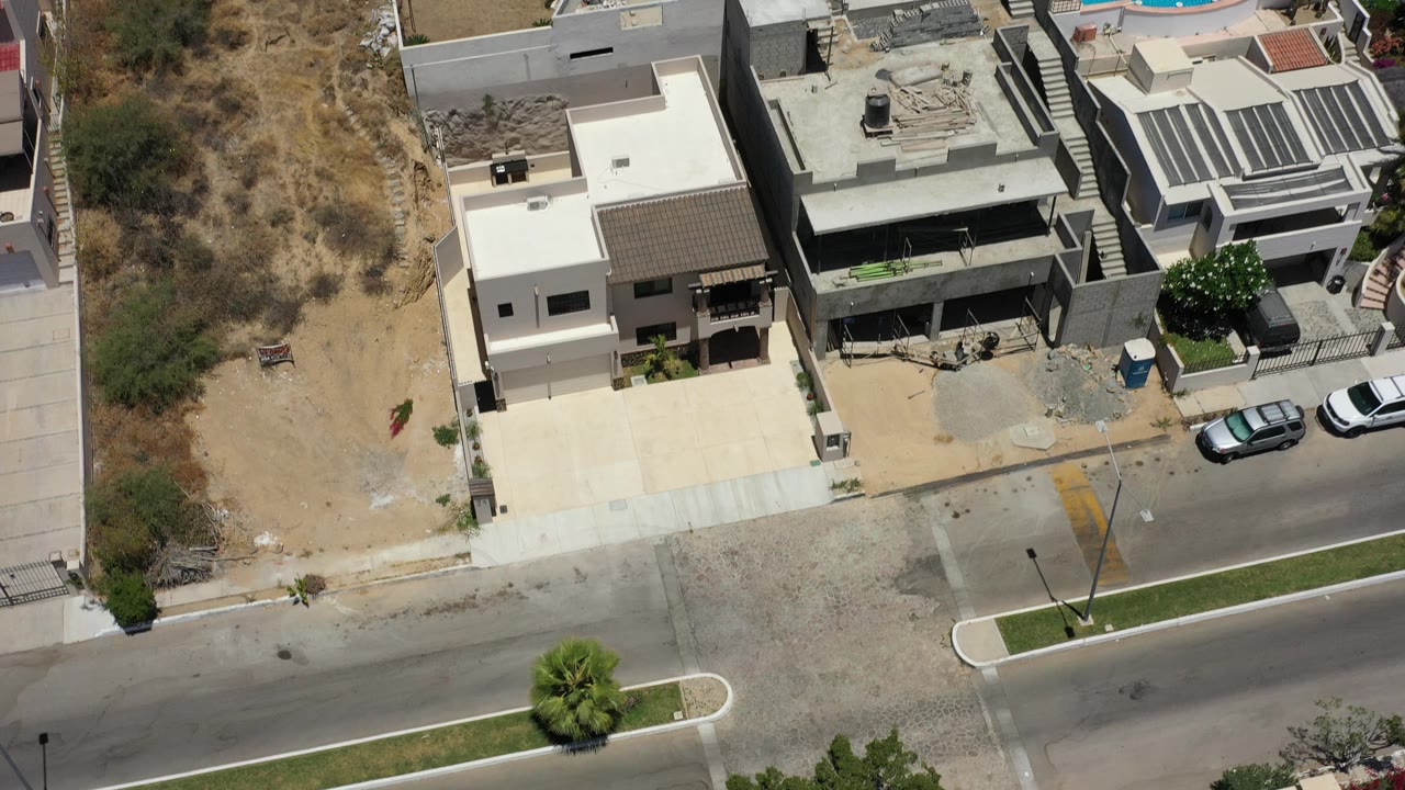 Aerial view of condos, road, parked vehicles, and a blue pool nearby.