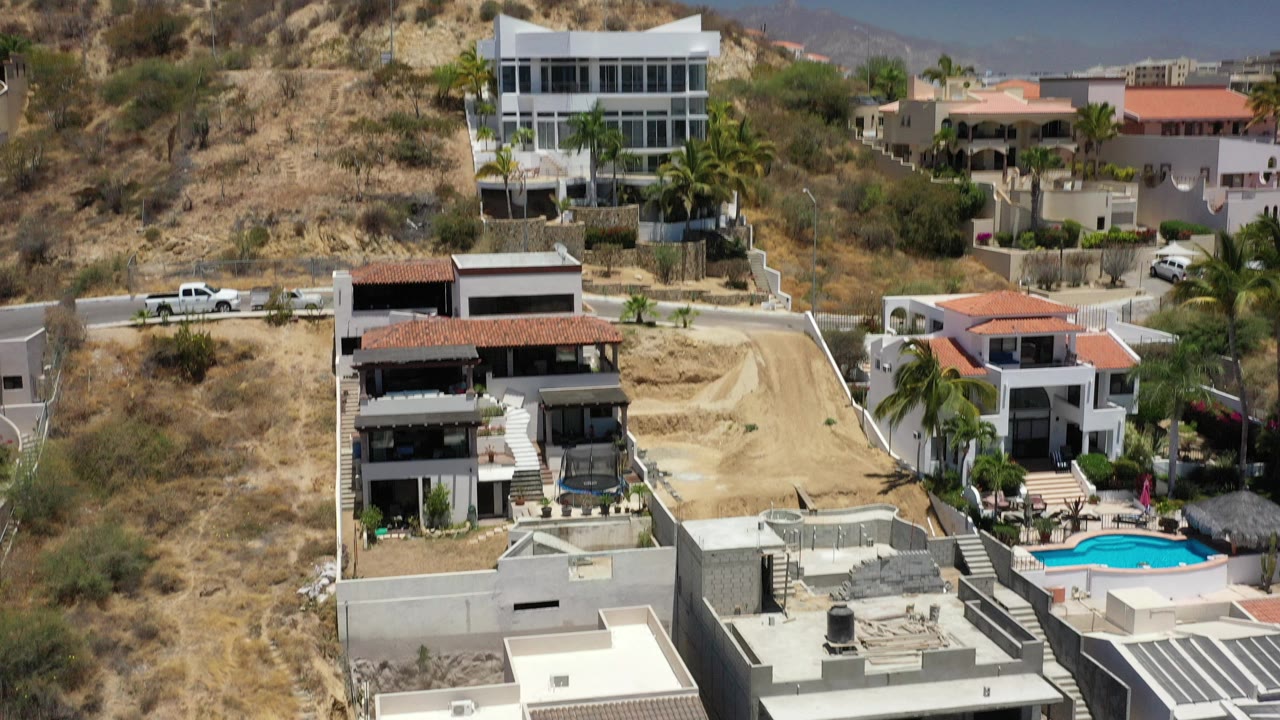 Modern homes on a dry hillside under blue sky