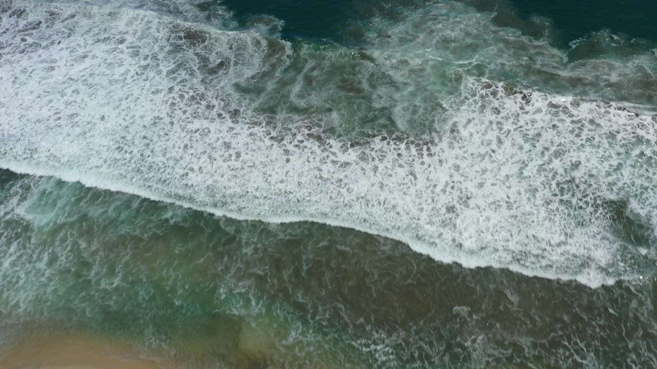 Wide overhead surf line with darker water beyond.