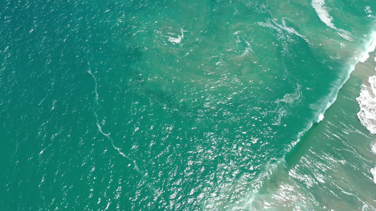 Overhead turquoise ocean with white surf along the right edge.
