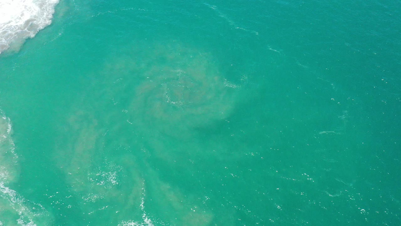 Turquoise ocean water with white surf at the upper left edge.