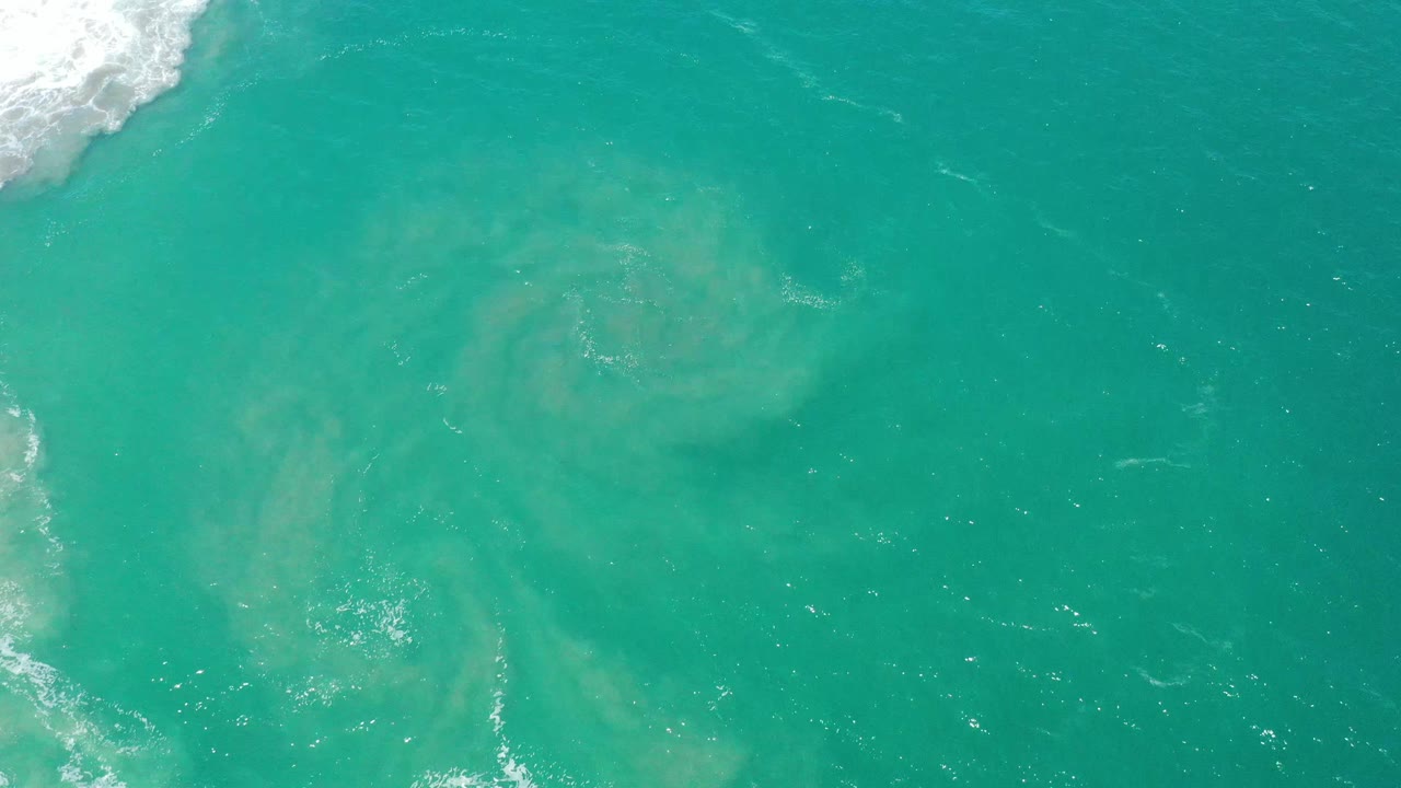 Overhead San Jose del Cabo ocean frame with blue-green water, pale suspended sediment below the surface, and no visible people.