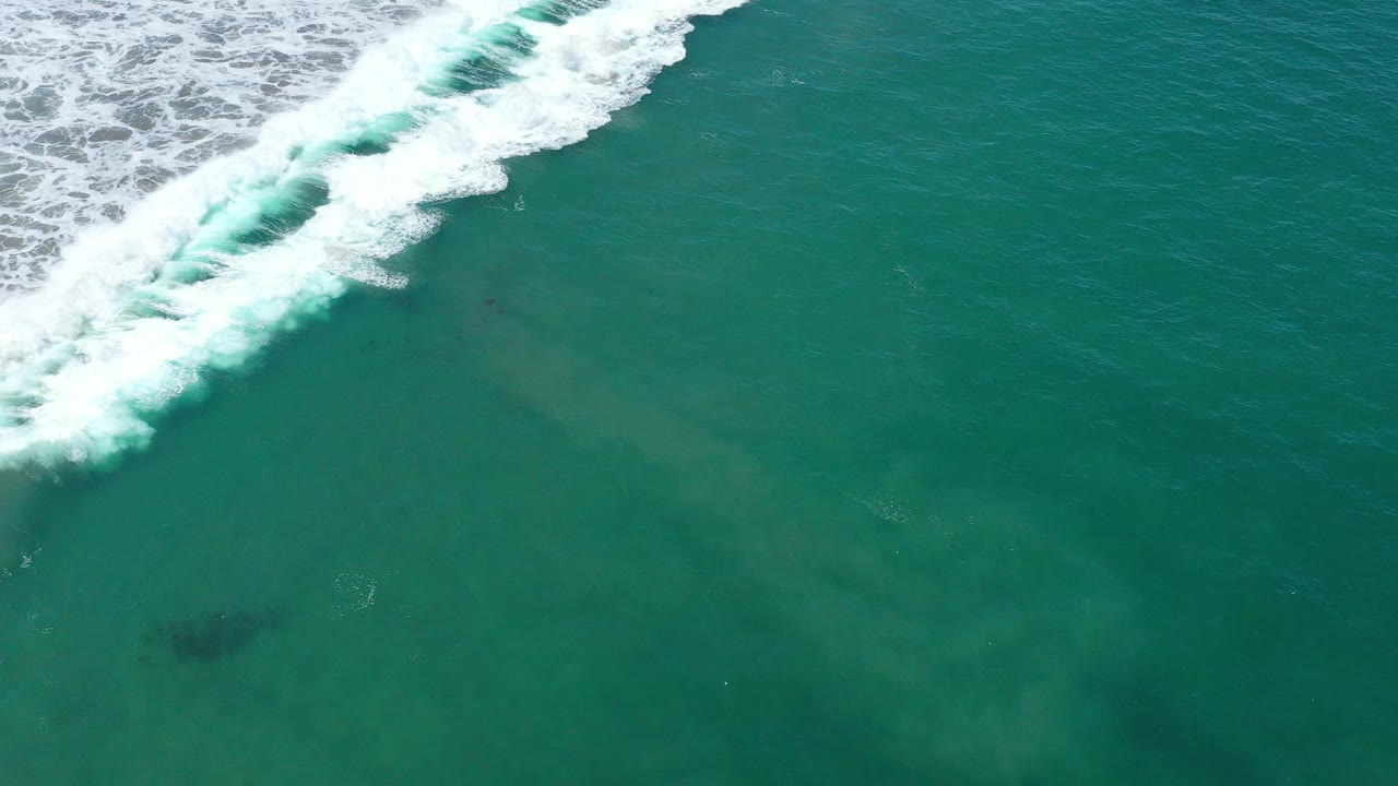 Breaking wave foam above clear green ocean water.