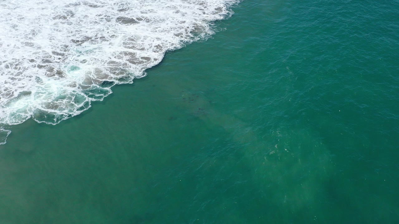 Green ocean water with white surf along the upper left edge.