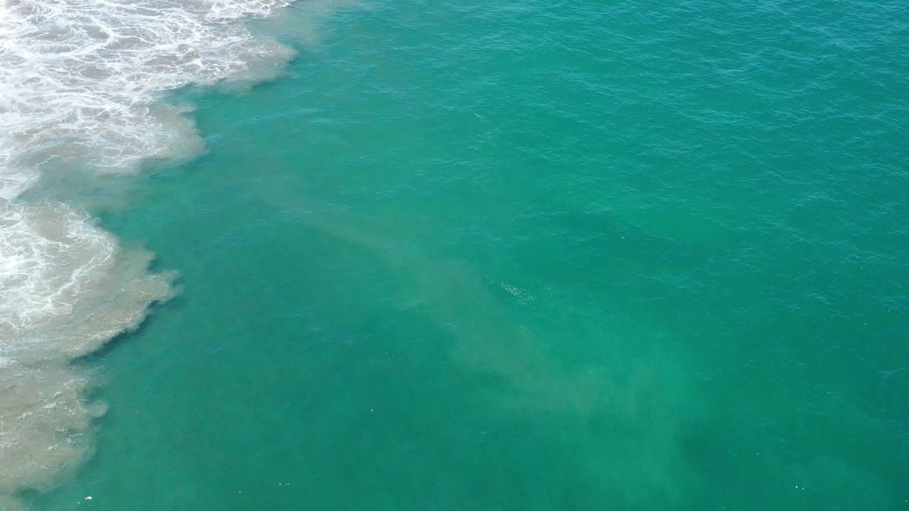 Aquamarine sea water fills the frame in San Jose del Cabo as the foamy shoreline edge sits slightly lower on the left, with no visible people.