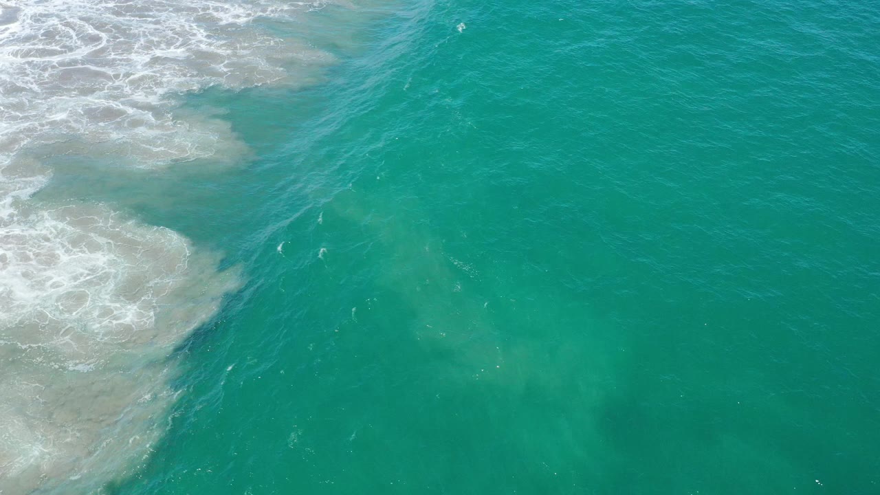 Open turquoise sea with surf foam near the top left.