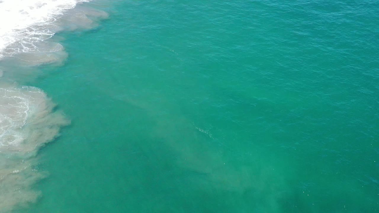 Teal ocean surface in San Jose Del Cabo, Mexico, with pale shallow-looking patches near the left side, fine ripples across the water, and no visible people.