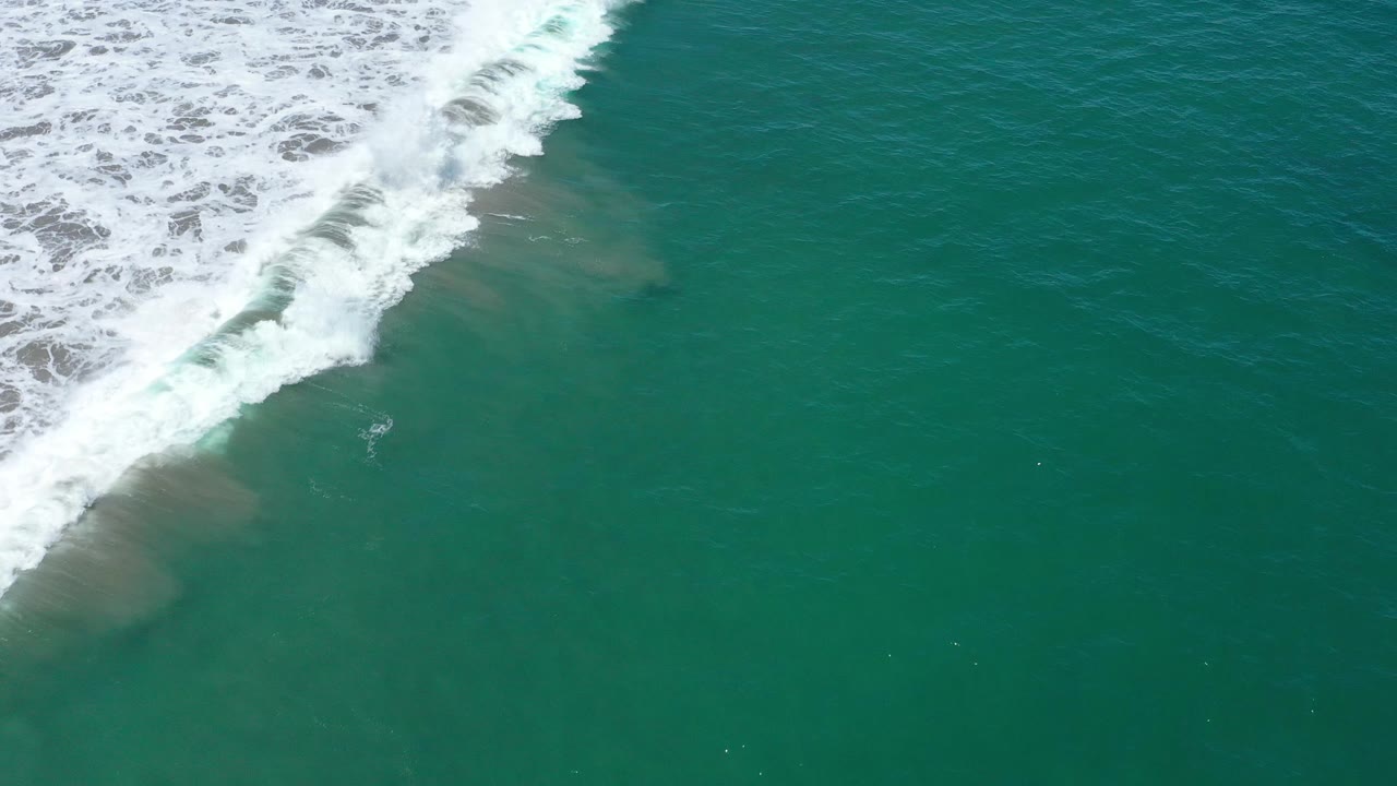 Breaking wave foam along the upper left over green sea.