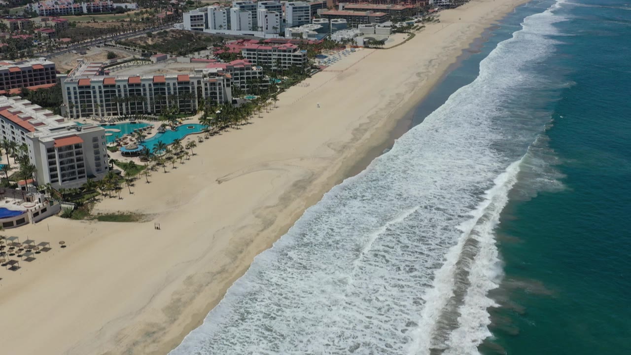 Diagonal aerial coastline with resort complex, beach, and ocean.