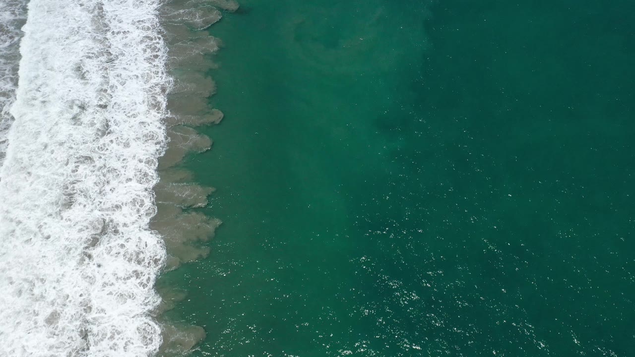 Surf line and sunlit teal water from above