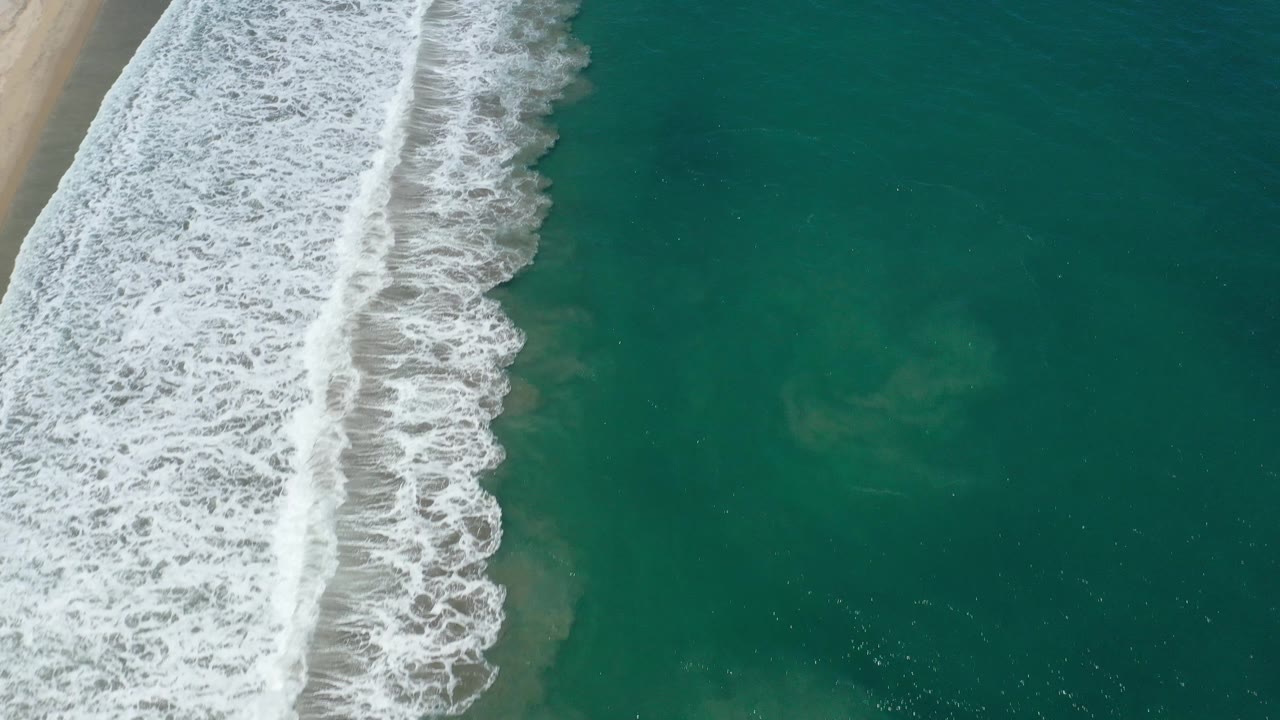 Wide overhead ocean view with seafoam near the left edge.