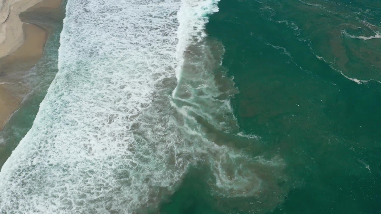 Foamy shoreline with dark patches under clear water