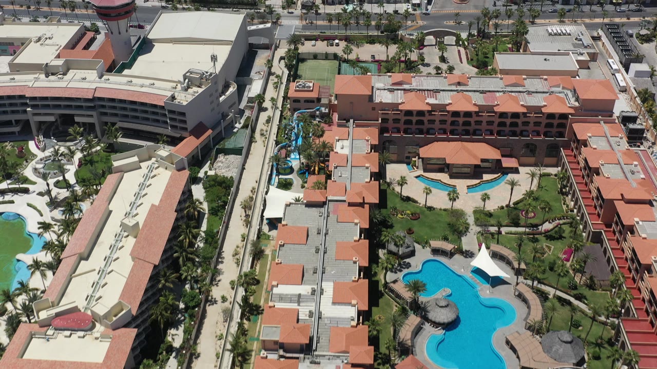 Drone-height view of a resort courtyard with pools and surrounding streets.
