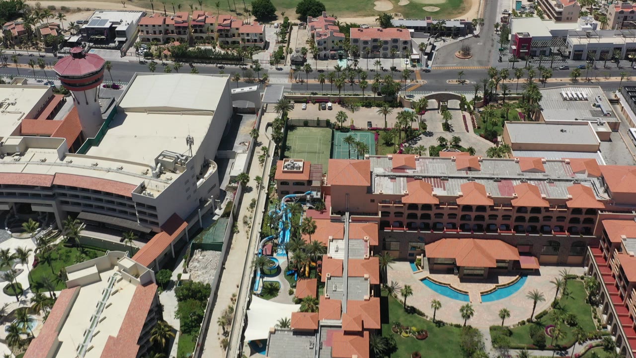 Overhead view of resort buildings, pool courtyard, water slide, road, and golf green.