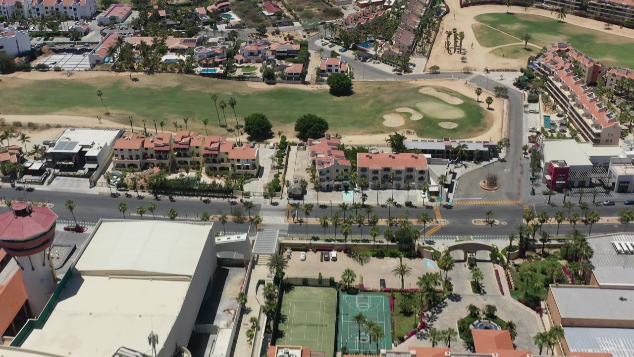 Aerial view of red-roofed buildings, tennis courts, road, and grass field.