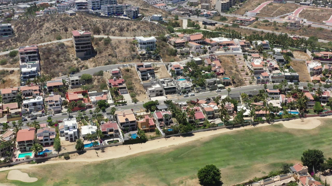 Aerial view of homes beside a golf course and hillside roads.