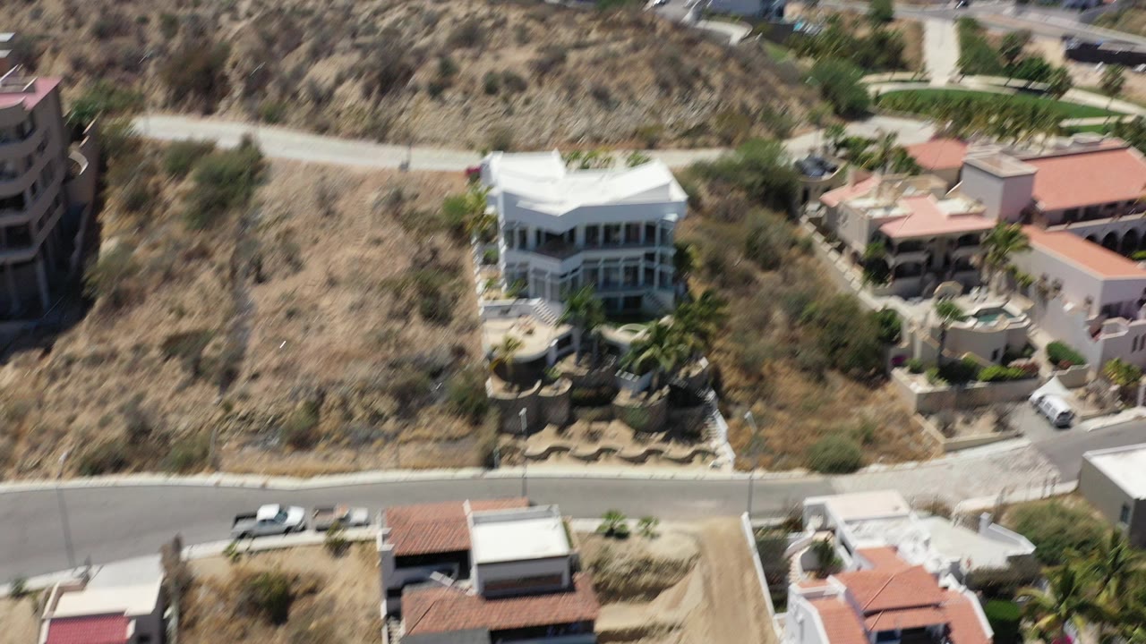 Aerial view of hillside homes with pools and dry terrain.