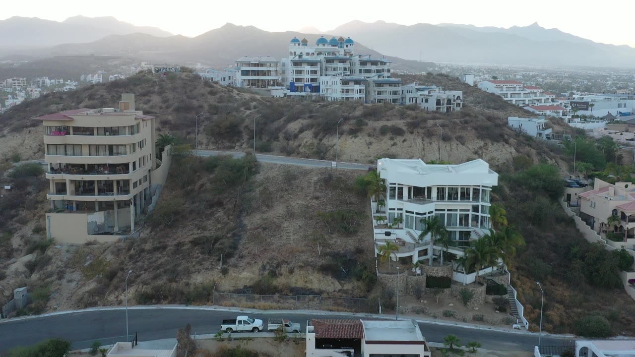 Hillside buildings, city blocks, and distant mountains at sunset.
