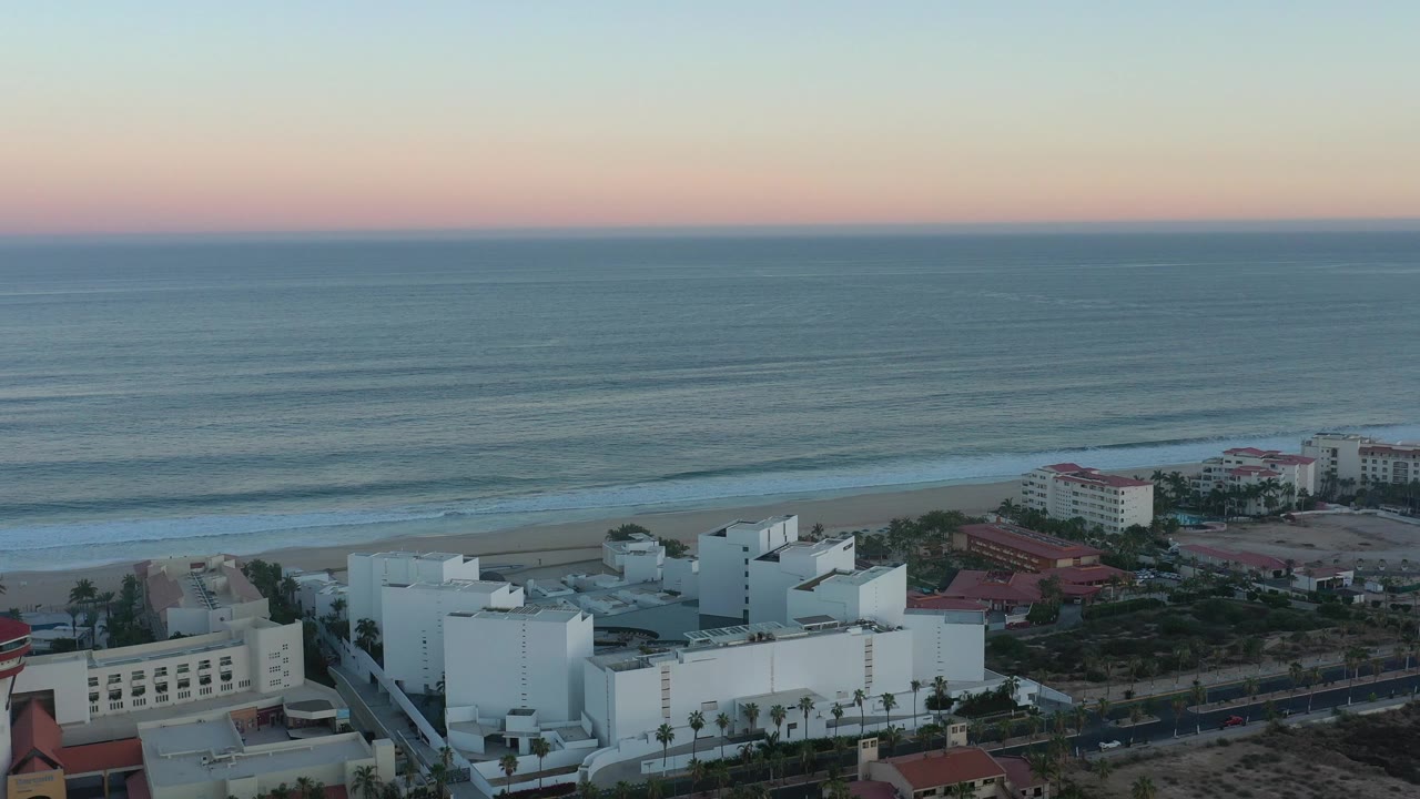 Oceanfront buildings and beach seen from above with soft evening light.