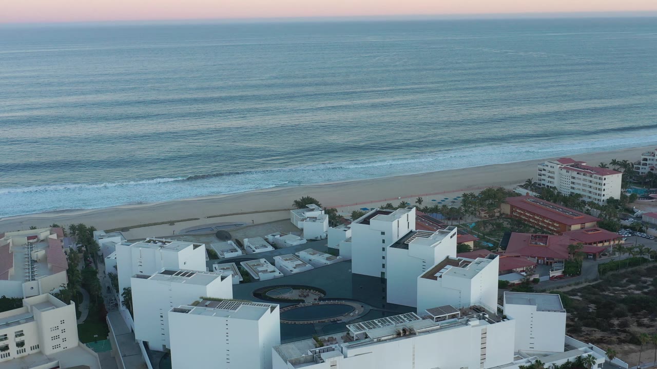 High coastal view of modern buildings, beach, surf, and ocean.