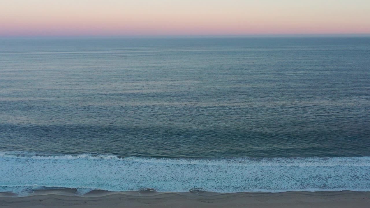Wide view of the San Jose del Cabo ocean at sunset, with a pastel sky above blue-green water and no visible people.