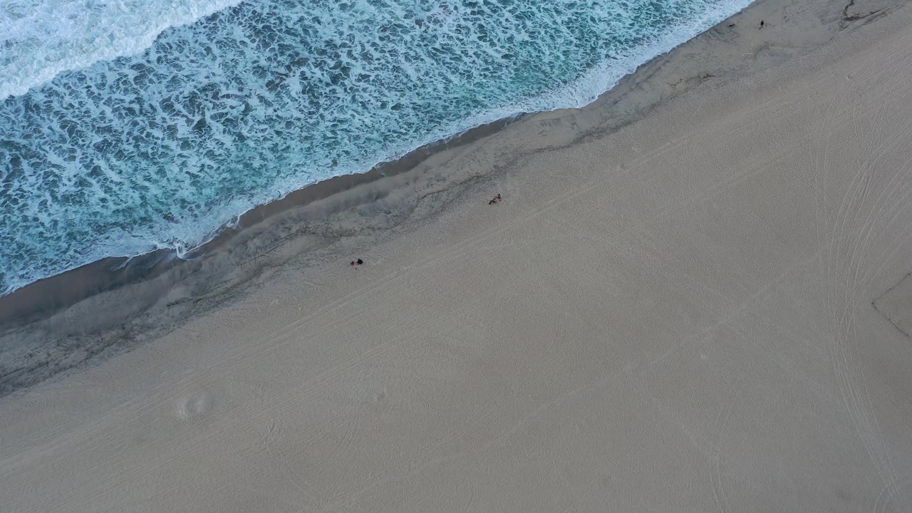Foam-covered wave edge beside smooth beach sand
