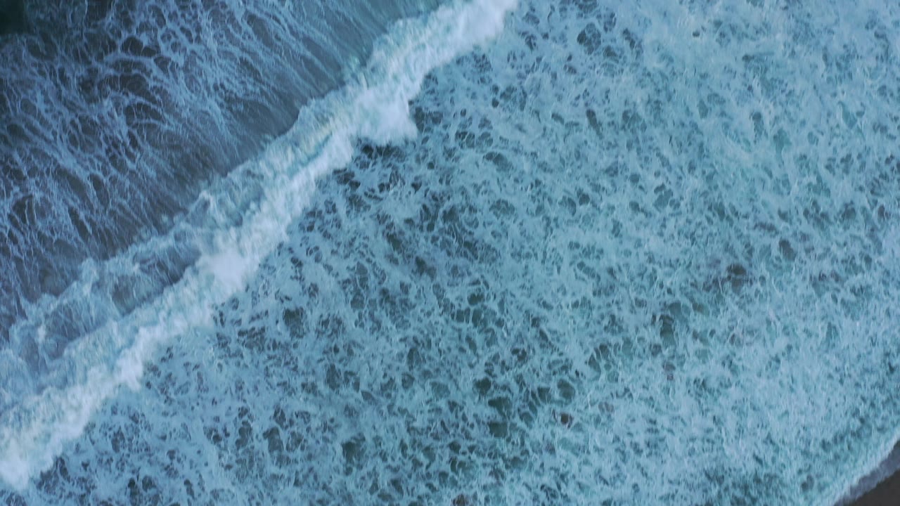 Overhead view of blue ocean water and white surf foam in San Jose del Cabo, Mexico, with no visible people.