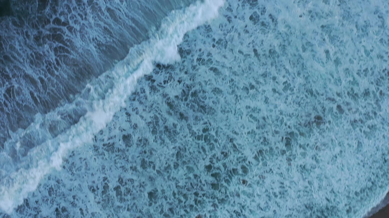 White cap surf spreads diagonally across blue ocean water in San Jose del Cabo, Mexico, with no visible people.