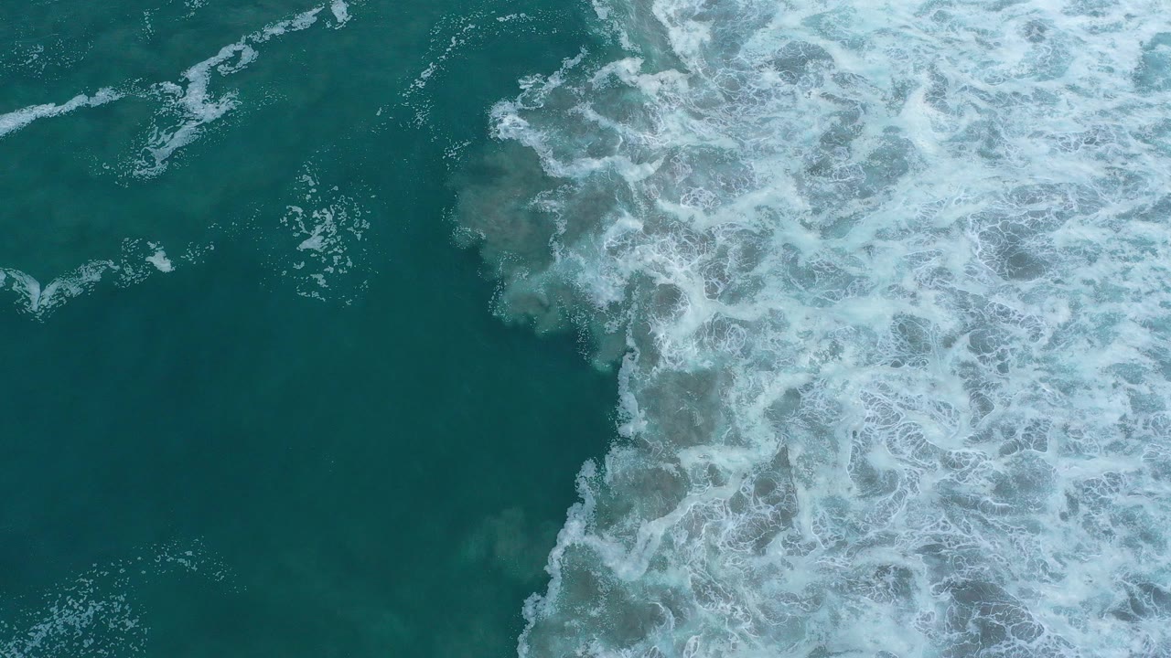 Overhead view of blue-green ocean and white breaking surf in San Jose del Cabo, Mexico, with no visible people.