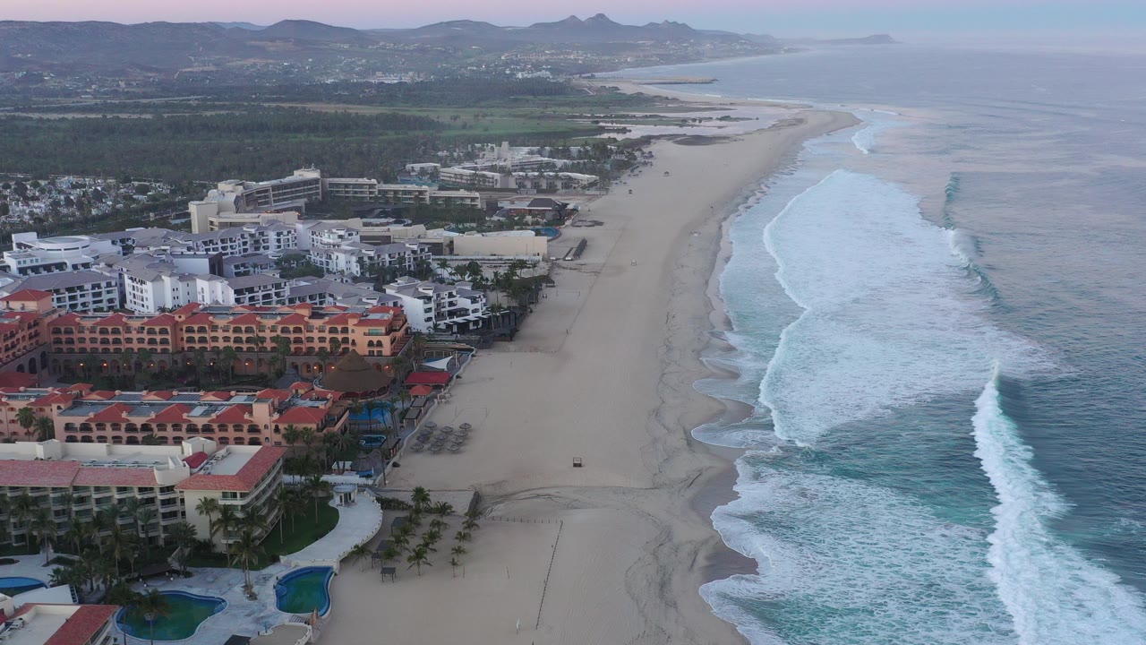 Aerial view of resort buildings beside a wide beach and surf