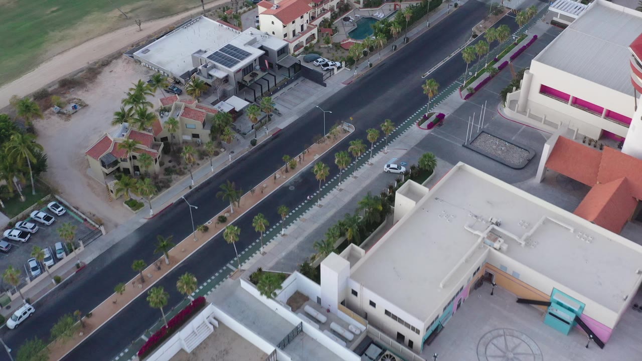 Aerial view of a broad street between modern buildings and landscaped sidewalks.