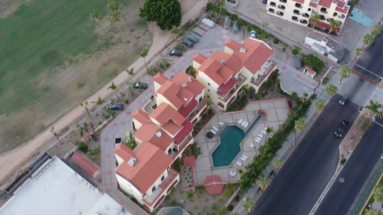 Overhead view of red-roof homes beside a road and green space.