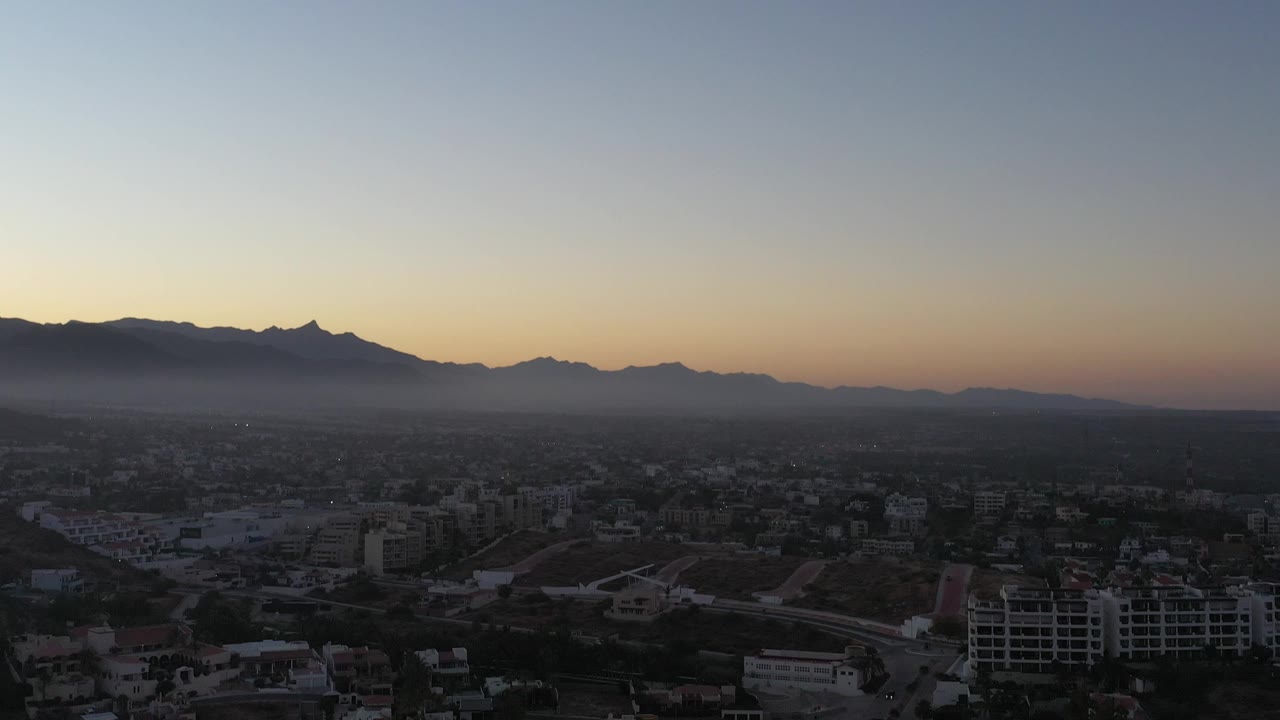High view over buildings with mountains silhouetted at sunset
