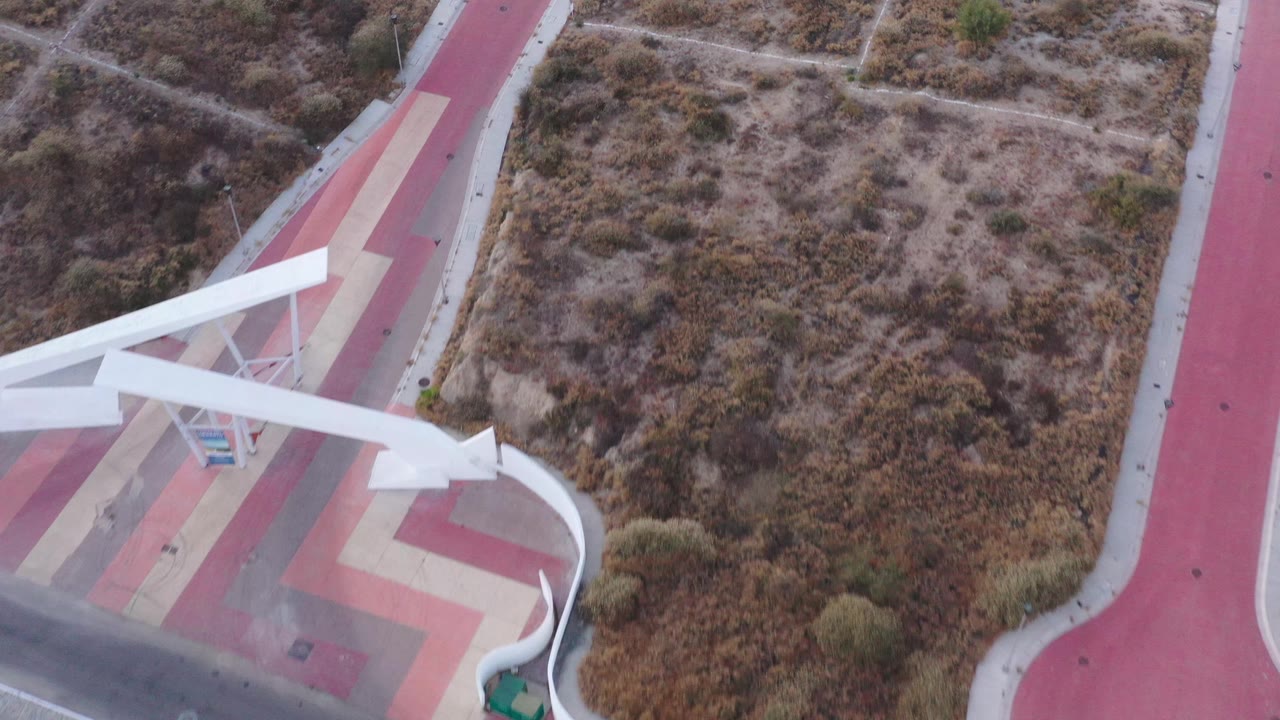 Colored path and scrubland with white tower at frame edge