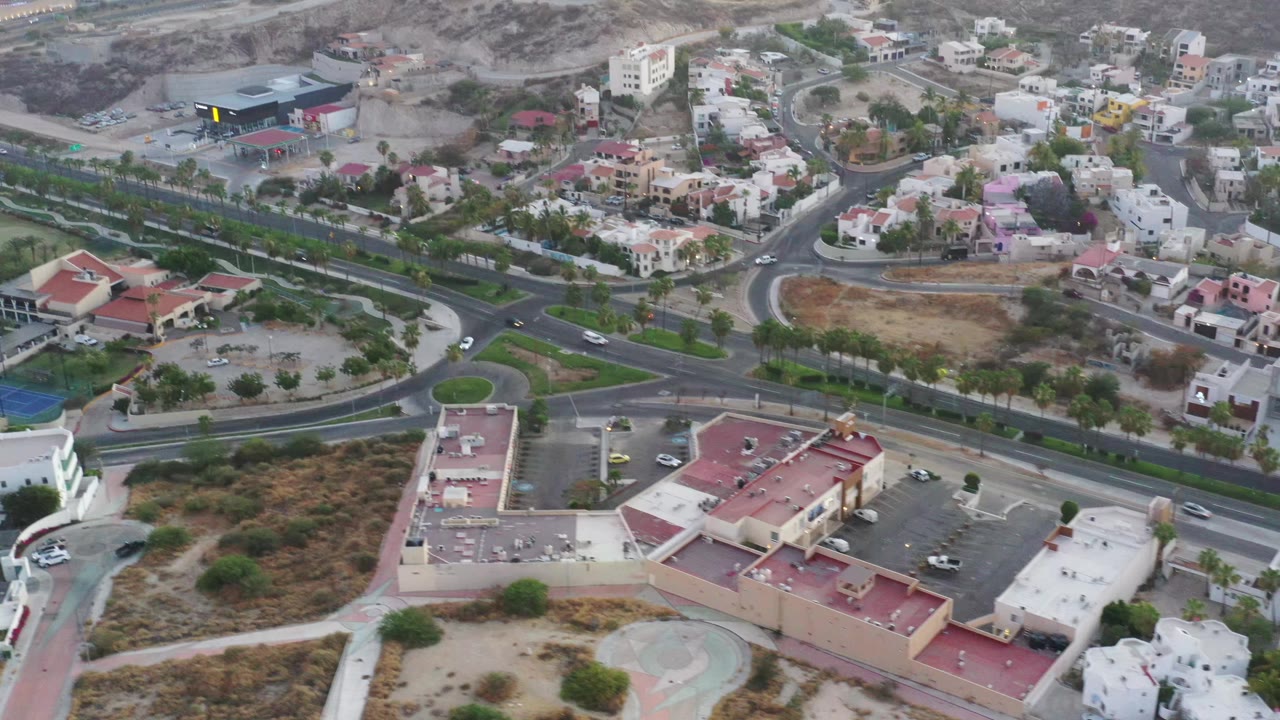 San Jose Del Cabo aerial view with a main road crossing the frame, clustered homes, landscaped strips, brown scrubland, and no visible people.