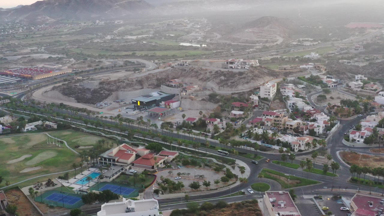 Aerial suburban landscape with roads, homes, golf course, and mountains.