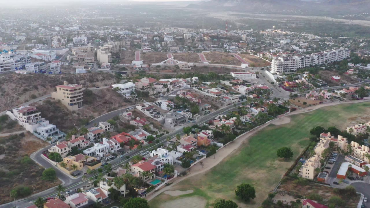 Aerial view of hillside homes, roads, town buildings, and mountains.