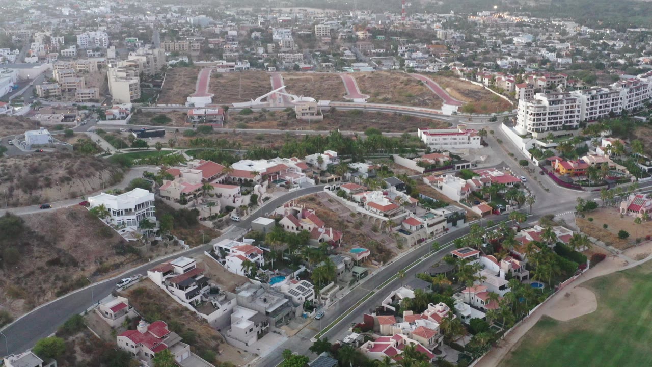 Aerial residential view with apartment blocks, roads, homes, and dry hillside.