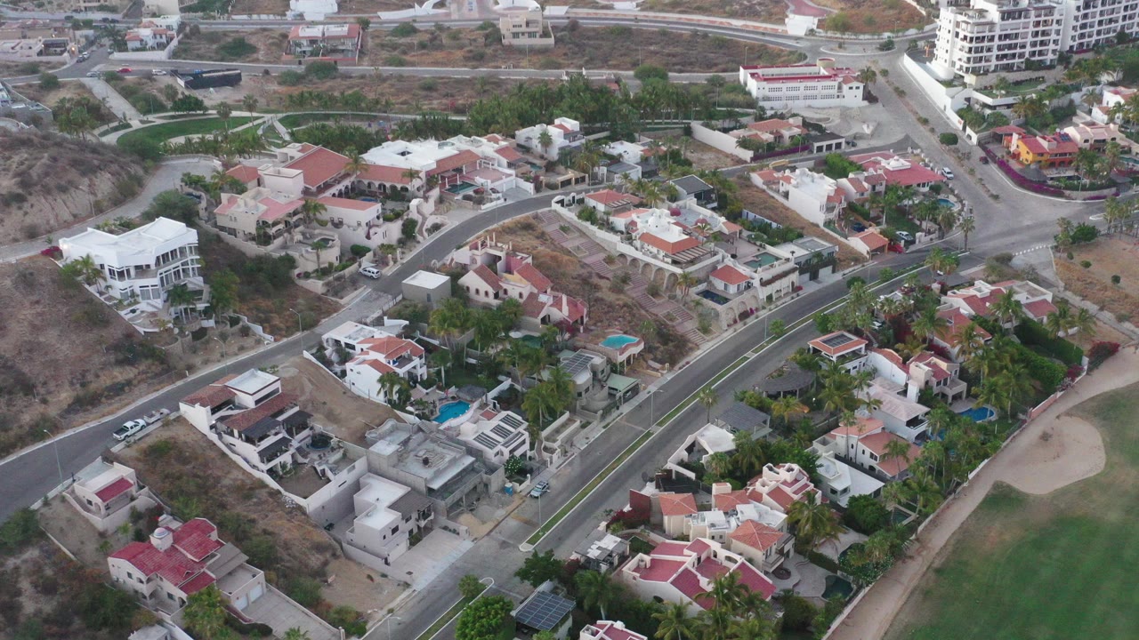 Overhead view of houses, roads, dry lots, and a golf course edge.