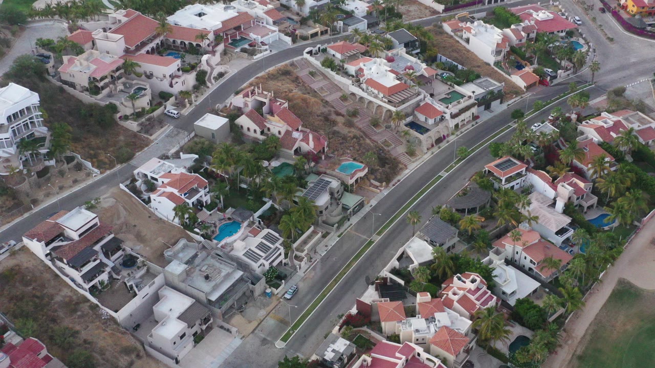 Aerial view of homes, pools, trees, and a curving residential road.