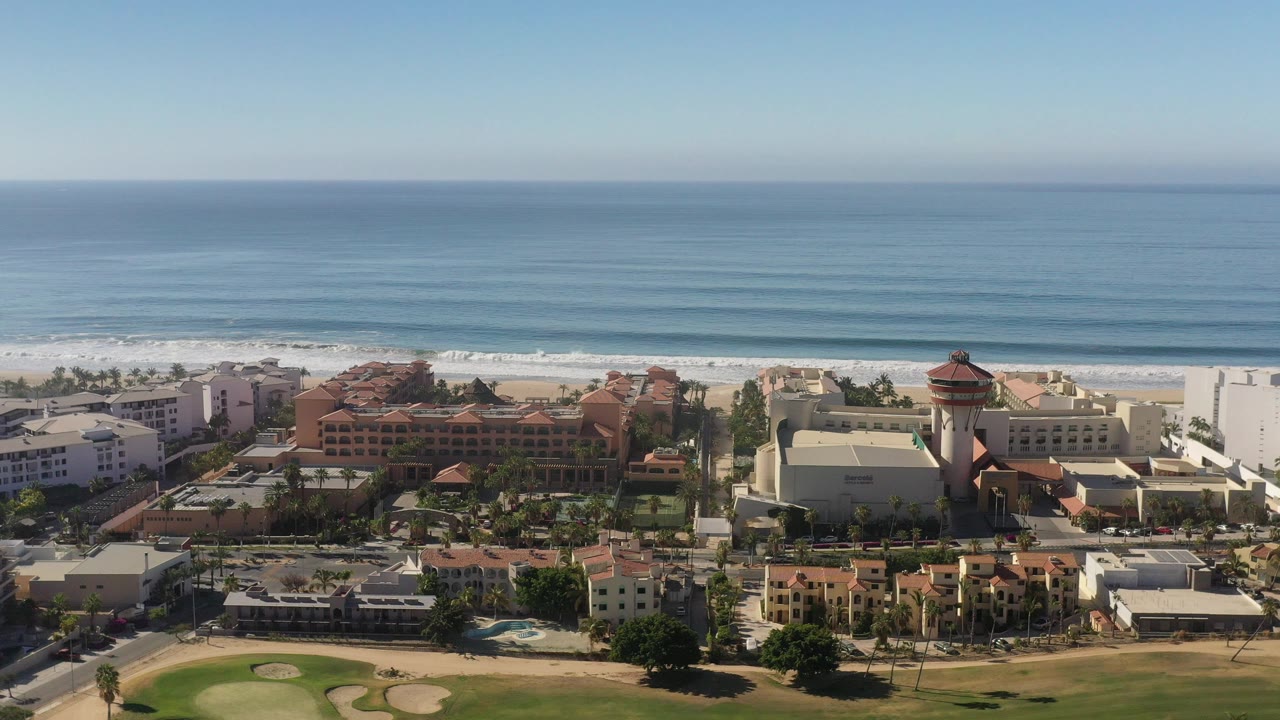 Aerial view of beachfront buildings beside a wide blue ocean.