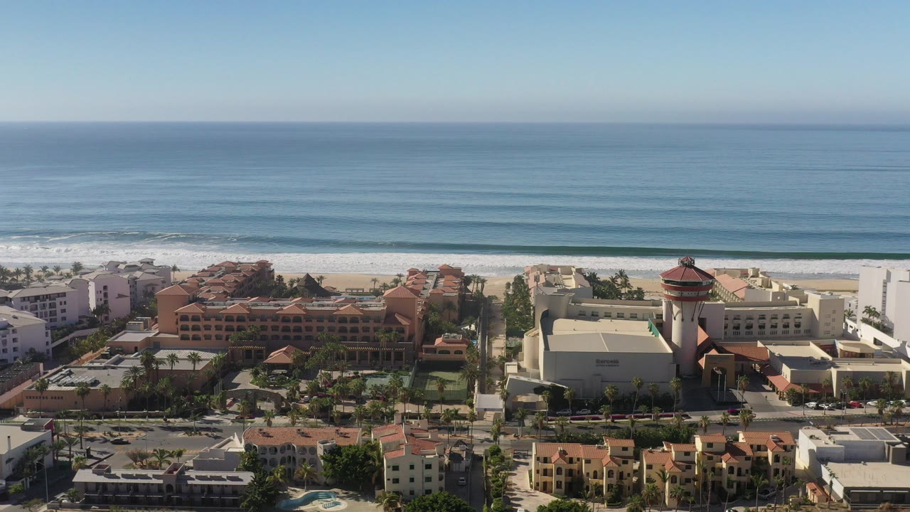 Aerial view of resort buildings beside a beach and blue ocean.