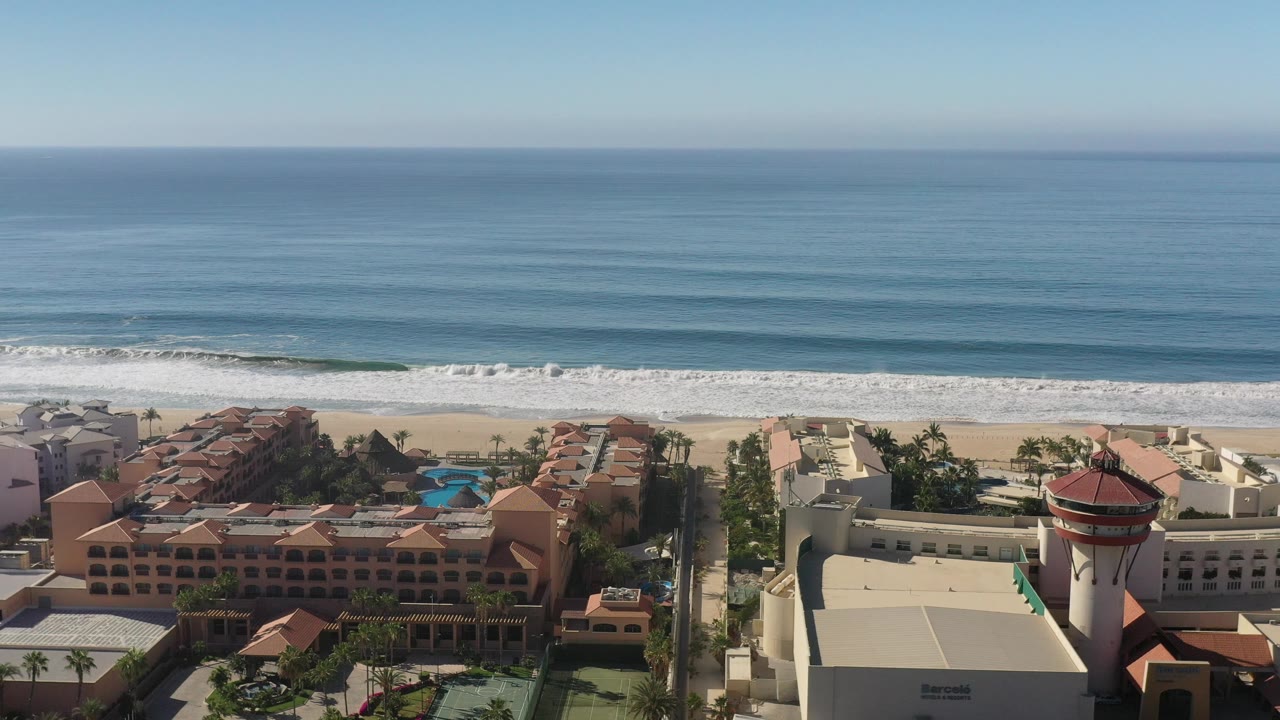 Wide ocean horizon above beachfront resort and surf.