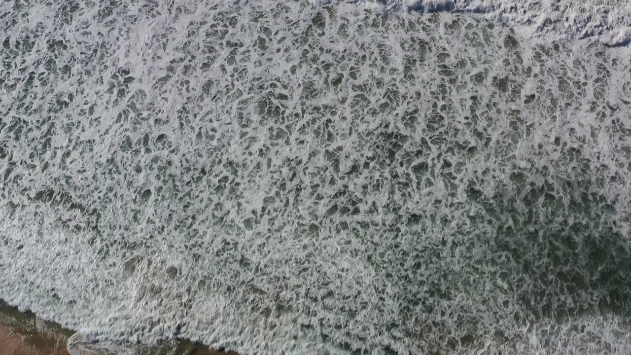 Dense white surf patterns fill the overhead frame.