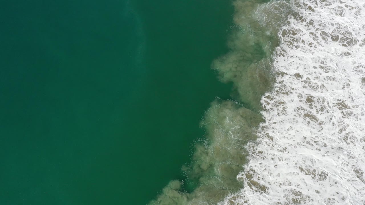 Foamy waves push into green water from the right side of frame.