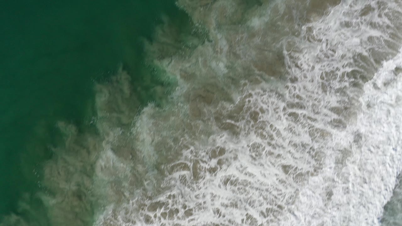 Foamy surf fills the right side of green ocean water.