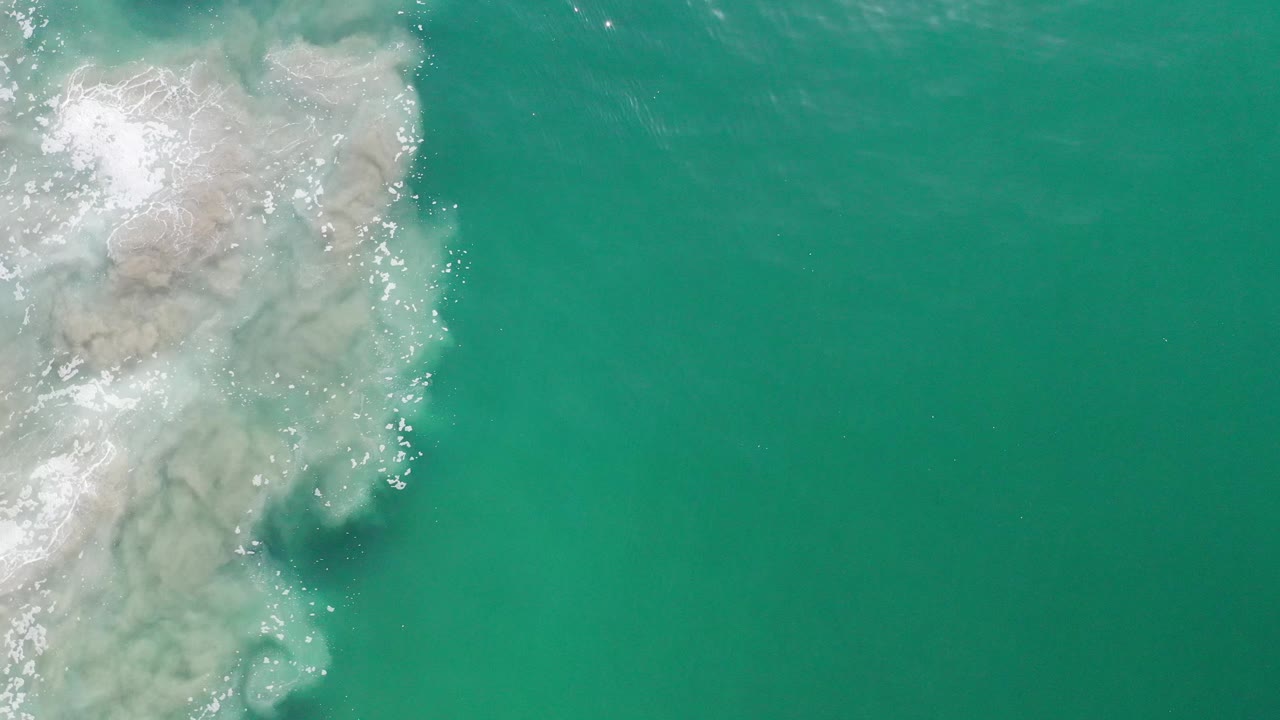 Green sea surface with pale underwater texture near the upper left.